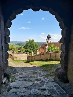 View through a stone Tor tor to a historic church and a landscape under a cloudy sky Riegersburg