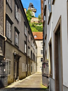 Narrow alleyway in the historic city centre, lined with old buildings with a tower in the
