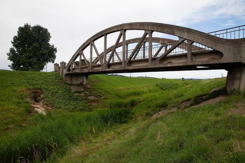 A concrete bridge over a grassy landscape that radiates peace and serenity Perschling flood channel