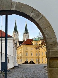 View through a stone gate onto a baroque building with two Gothic church towers, Klosterneuburg