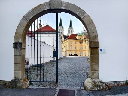 View through a Tor tor to a cobbled courtyard and church towers of a historic building,