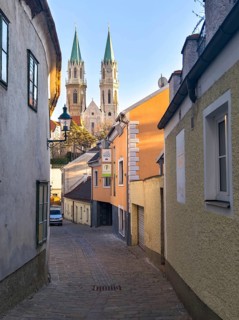 Narrow old town path with a view of high church towers in the warm light of late day,