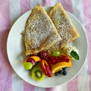 Crepes on a plate with fresh fruit, icing sugar and a decorative fruit garnish Lower Austria