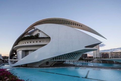 Building with curved white design next to a turquoise-coloured pool under the evening sky Opera