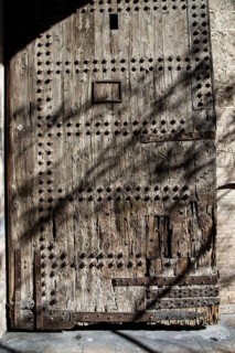 A solid, antique wooden door full of texture and nails