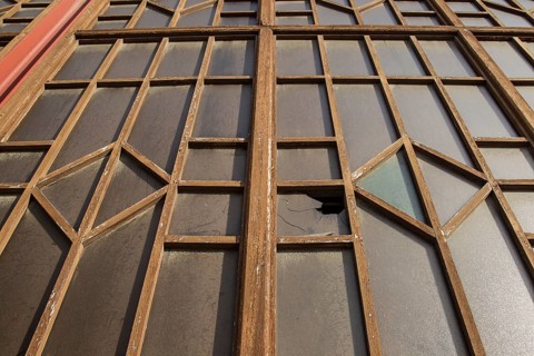 A window with broken glass and a complex metal structure