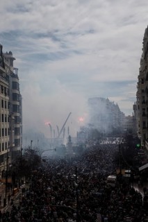 Tightly packed crowd under clouds of smoke on a city street MascletÃ¡ de Fallas
