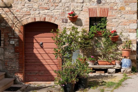 Tuscany country house detail with flower bench planter next to old wooden door quarry stone wall,