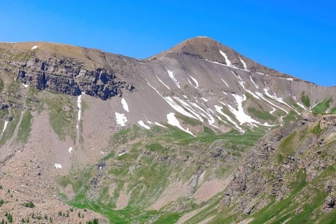 View to the rear eroded steep rocky slope mountainside slope with gravel rock thawing snow remains
