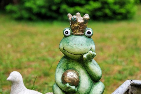 Sculpture of a frog king with crown and golden ball, decoration in the garden, Schloss