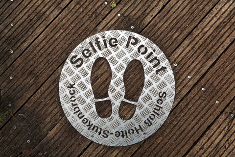 Selfie point, metal plate, shoe prints on a plank path at the source of the River Ems near Schloss