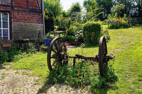Rusted metal wheels on an axle, decoration in a garden, country inn in summer, Rischenau, LÃ¼gde,