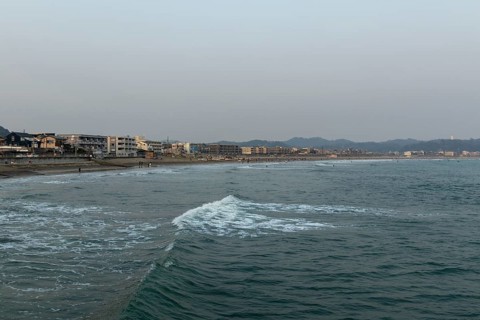 Houses on the seafront and surfers in the surf at dusk on the beach in Kamakura, Kanagawa