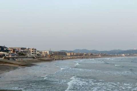 Houses on the seafront and surfers in the surf at dusk on the beach in Kamakura, Kanagawa