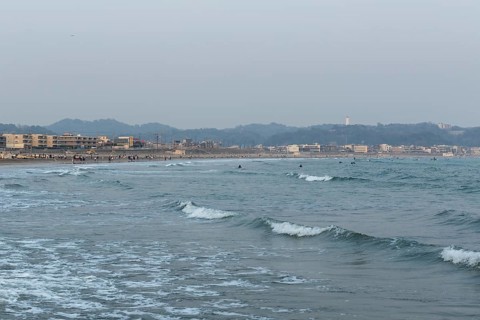 Houses on the seafront and surfers in the surf at dusk on the beach in Kamakura, Kanagawa