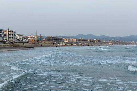 Houses on the seafront and surfers in the surf at dusk on the beach in Kamakura, Kanagawa