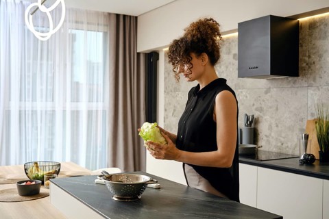 In a contemporary kitchen filled with natural light, a woman holds a head of lettuce while