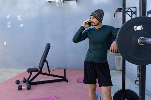 Athlete taking a break from an intense workout, leaning against a weightlifting rack while engaged