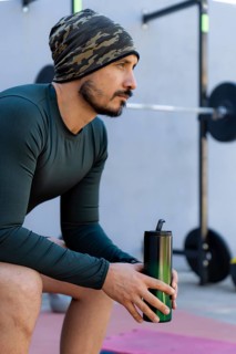 Athlete sitting and taking a break after an intense workout, holding a water bottle and emphasizing