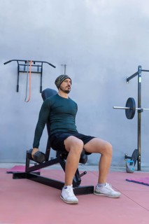 Athlete is strengthening his deltoids by performing seated lateral raises with dumbbells in an