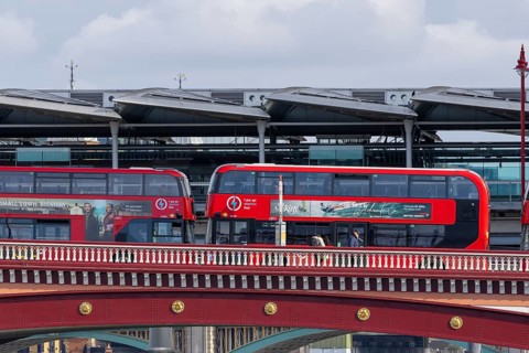 Two red double decker buses driving over a bridge, City of London, England, United Kingdom