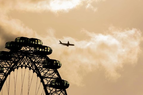 The London Eye wheel with a jet aircraft flying behind at sunset, City of London, England, United
