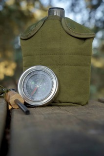 Survival kit essentials including compass, canteen, and firesteel are ready for outdoor adventure