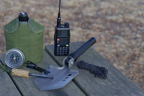 Essential survival gear including walkie talkie, compass, folding shovel, and fire starter are