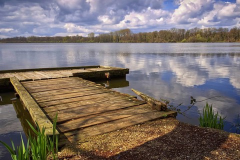 Old wooden jetty on the lake (Krickenbecker Seen) with clouds reflecting on the water, Nettetal