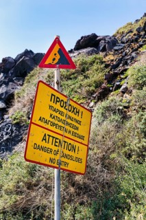 Signs warning of landslide and falling rocks, no entry, cliffs, Red Beach, Kokkini Paralia,