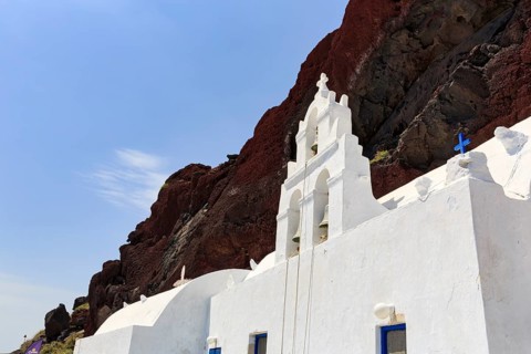 Agios Nikolaos Mavrorachidi, chapel with bell tower in front of red rock face, volcanic rock,