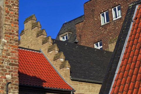 Different roof styles and brick wall under a clear blue sky, DÃ¼sseldorf