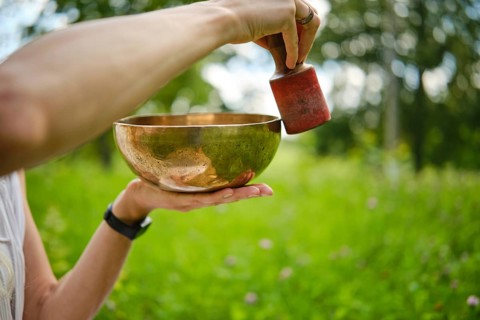 Engaging in meditation with singing bowls in a serene outdoor setting during daylight hours