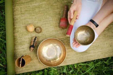 A mindful relaxation practice, playing singing bowls on a natural mat surrounded by grass, overhead