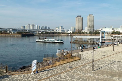 Strollers on the promenade and futuristic Tokyo Cruise Water Bus Queen Emeraldas, excursion boat