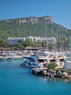 Kemer marina filled with numerous boats and yachts with Calis Hill in the background. A lighthouse