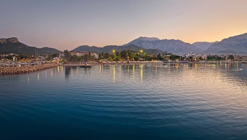 Dusk scene in Kemer, Turkey, showing the town illuminated coastline and beach, reflected