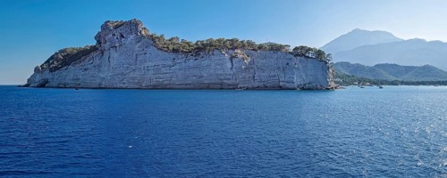 Vibrant seascape panorama with beautiful Turkish mediterranean coastline lined with tree covered