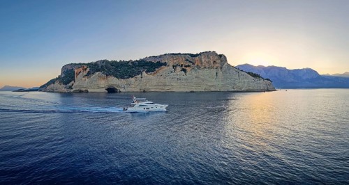Evening seascape panorama with a boat cruising away on the blue sea, near the Pirate Cave in Kemer
