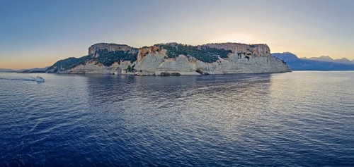Evening seascape panorama with a boat cruising away on the blue sea, near the Pirate Cave in Kemer