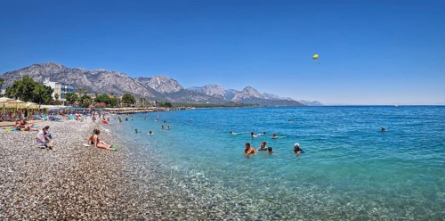 KEMER, TURKEY - JULY 5, 2025 Kemer municipality public beach with vibrant pebble under a clear,