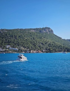 Vibrant seascape with a boat cruising away on the blue sea, leaving a white wake. Beautiful Turkish