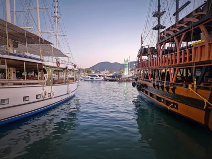 Kemer marina at dusk, filled with multiple docked boats. Lights of the harbor and the resort