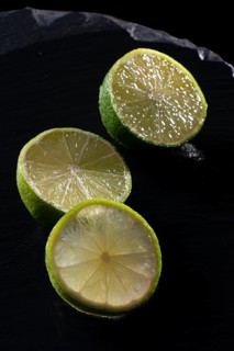 Three lime slices on a black stone plate