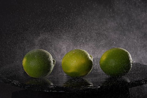 Three limes on a stone slab with drops of water