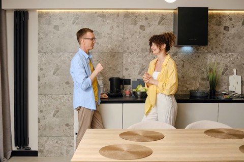 A man and woman talking in a stylish kitchen. They smile at each other, sharing ideas amidst fresh