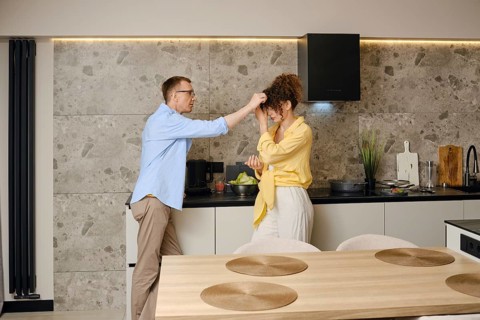 Couple enjoying a playful moment in a modern kitchen while preparing a meal together