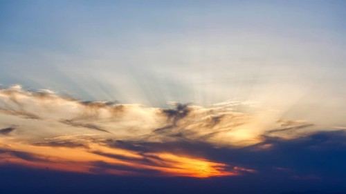 Sunset behind cloud cover, sunbeams, Oia, Thira, Santorini, Cyclades, Greece