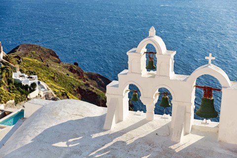 White bell tower of an orthodox church overlooking the sea, coastline, Oia, Santorini, Cyclades,