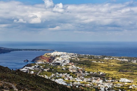 Coastline with view of the village of Oia, hiker on hiking trail from Fira to Oia, Thira,